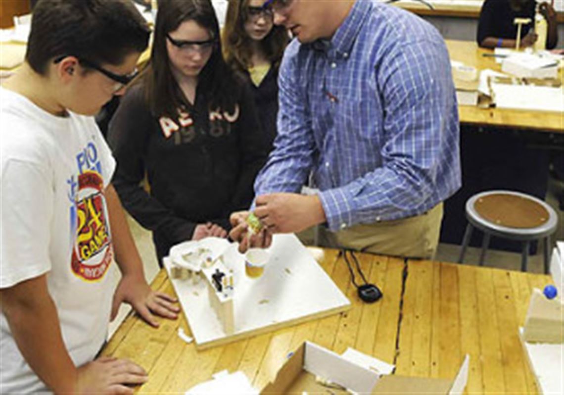 Post-Gazette photo
 Teacher Josh Cramer, right, helps seventh- grade pupils Josh Faust, left, and Sara Kaminski with their Rube Goldberg device in his Science of Technology class.
