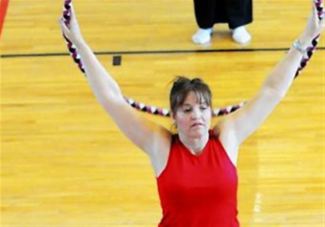 Three aerobics students stretch using hula hoops during a fitness class that combines hooping and Pilates at the Peters Township Community Recreation Center.
