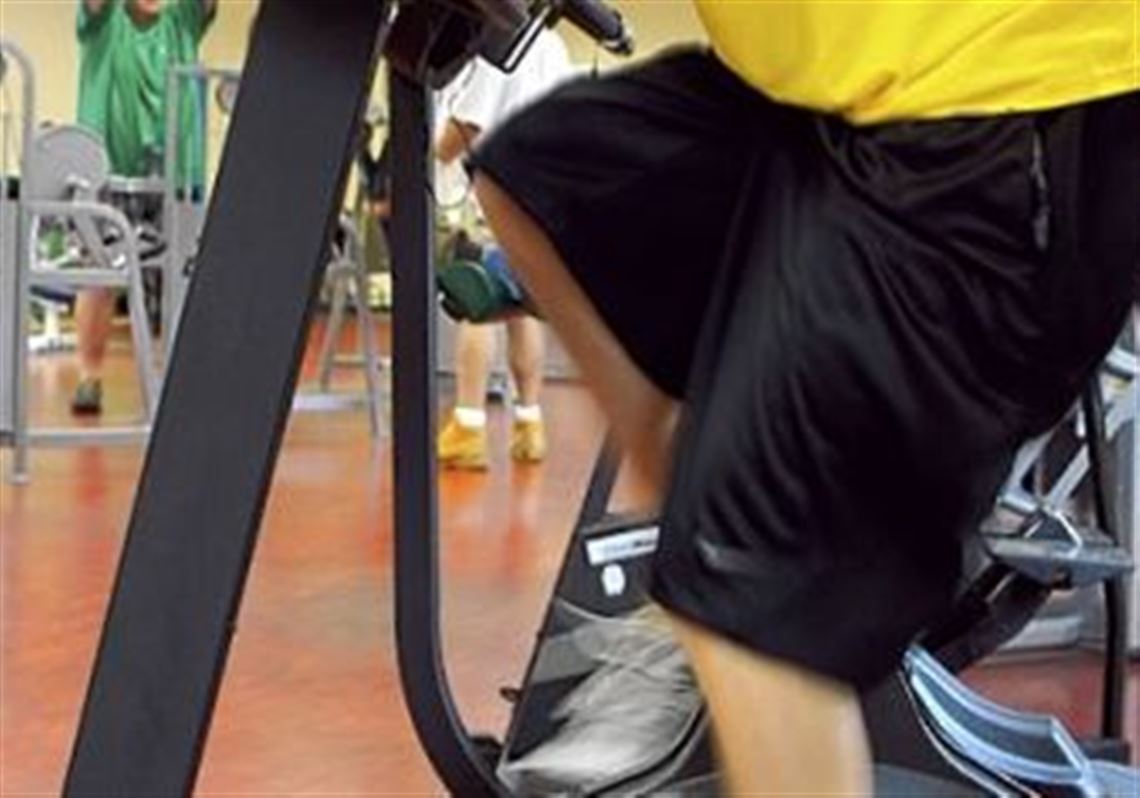 Triathlete Brad Davern churns away on the exercise bike during his daily workout at the fitness club at the Carnegie Library in Munhall.