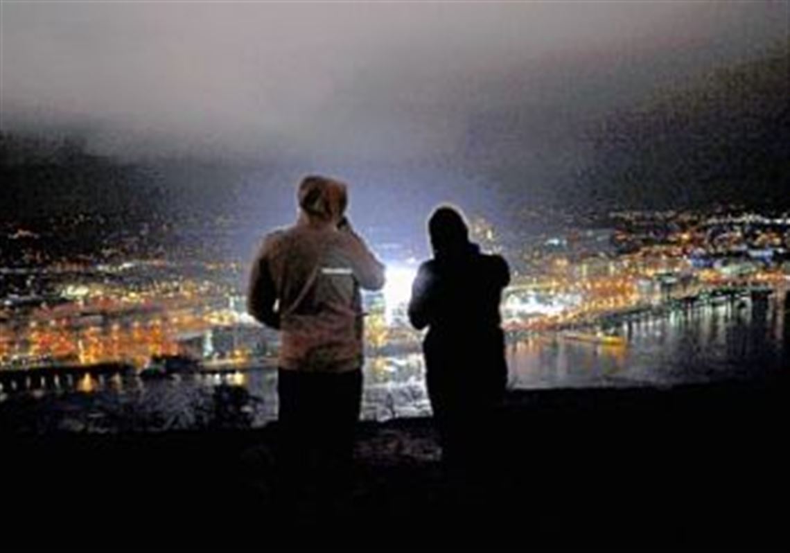 A man and a woman look out over a lit Heinz Field hours before the start of the Winter Classic from Mt. Washington last night.