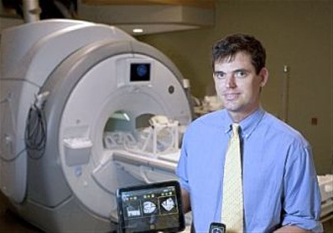 Stanford University research associate Andrew B. Holbrook holds an HP TouchPad Tablet and a Palm Pixi Plus, which contain apps he's developing that allow users to control an MRI scanner.