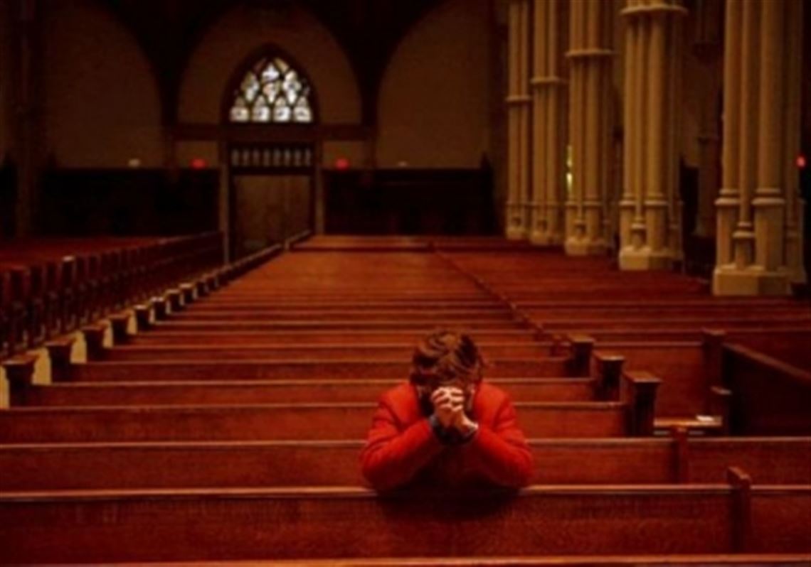 A woman kneels to pray Wednesday for Pope Francis at St. Paul Cathedral in Oakland.
