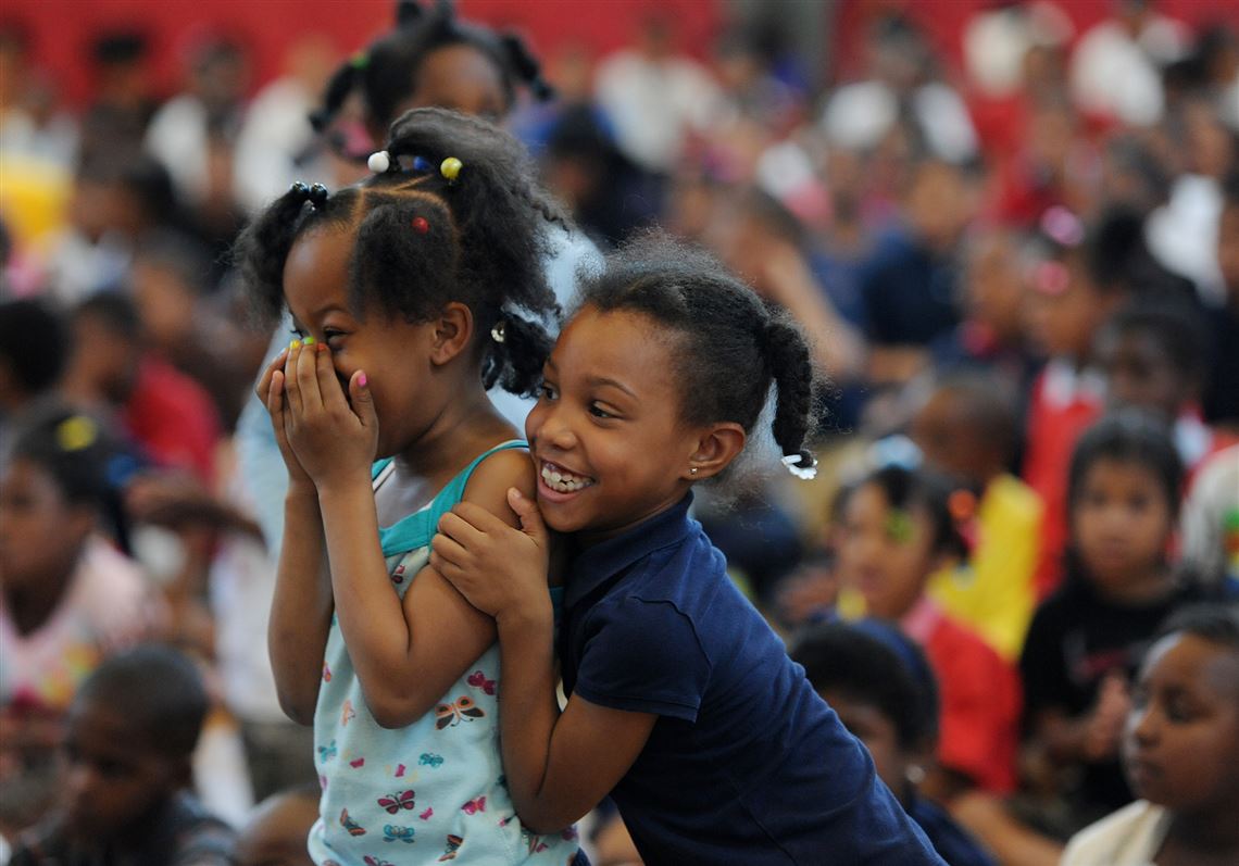 First graders Davaisha Bush, left, and Miranda Diggs react as their names are called during the United Way Be There 30-Day Challenge  ceremony honoring students' attendance at Pittsburgh Faison K-5 in Homewood on Friday.