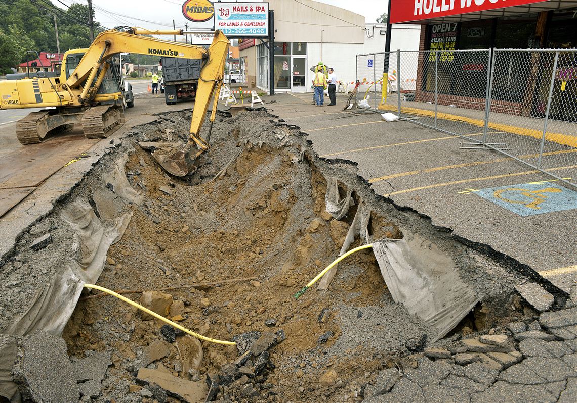 Workers dig down in the parking lot of Hollywood Tans on McKnight Road to repair a sinkhole that collapsed Aug. 12.