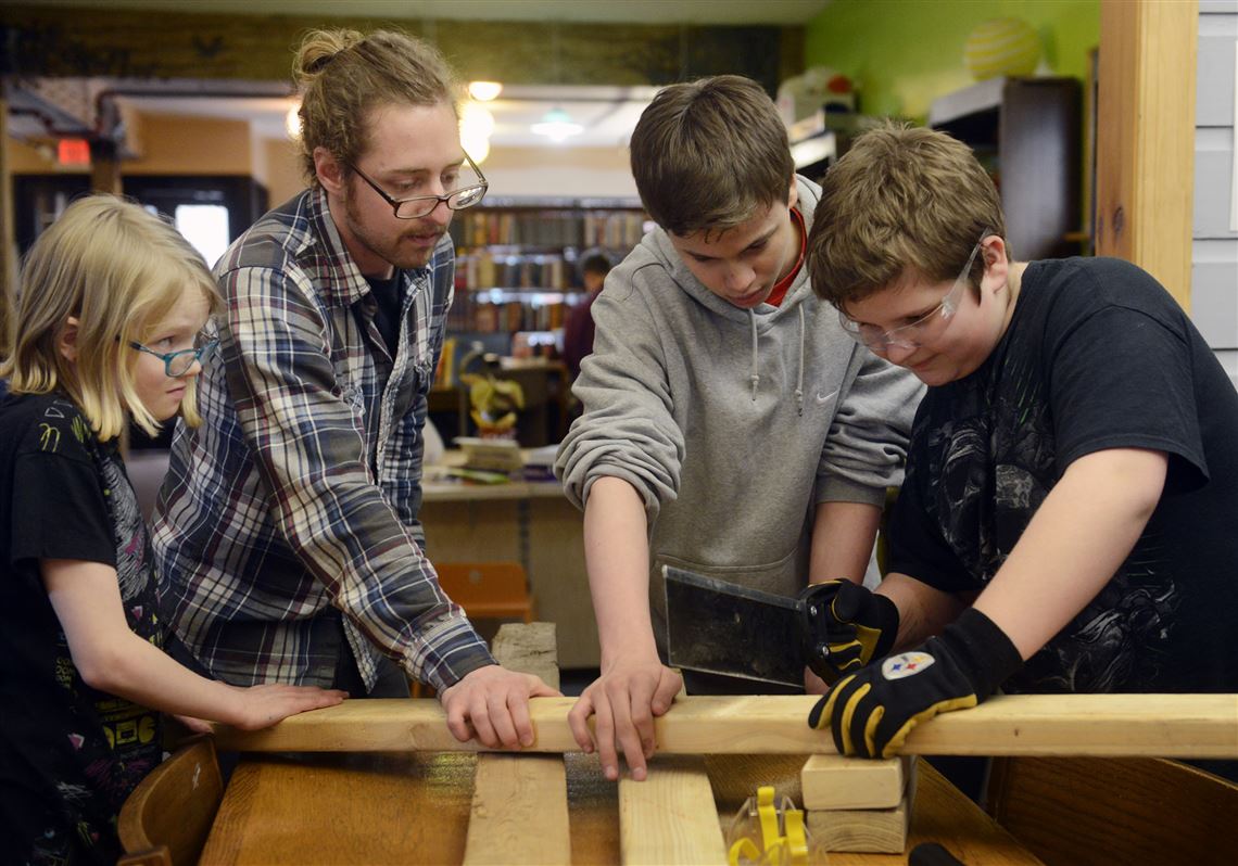 From left, Skylar Buchman, 10; Anthony Stewart, president and environmental director of Deco Resources; Codie McCarthy, 14; and Alex Zbel, 10, all of Millvale, at the Maker Thursdays at Millvale Community Library, where they work at the plant stands for an aquaponics system they will be constructing at the library.