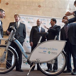 One of the bicycles that will be a part of Pittsburgh's new bike-sharing system is unveiled Wednesday. Through the program, called Healthy Ride, 500 bikes will be placed at 50 stations throughout the city. Among those attending were, from left, David White of Pittsburgh Bike Share; Allegheny County Executive Rich Ritzgerald; Dan Onorato, executive vice president of Highmark Health; Mayor Bill Peduto; and Dr. James Sferra, of the Allegheny Health Network.