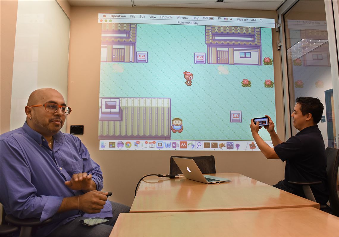Anind Dey, left, of CMU, is leading the team coordinating with Google and other universities to use Internet sensors in many locations to allow connectivity beyond current use. Ph.D. candidate Adrian de Freitas, right, demonstrates connectivity through sensors with his smart phone.
