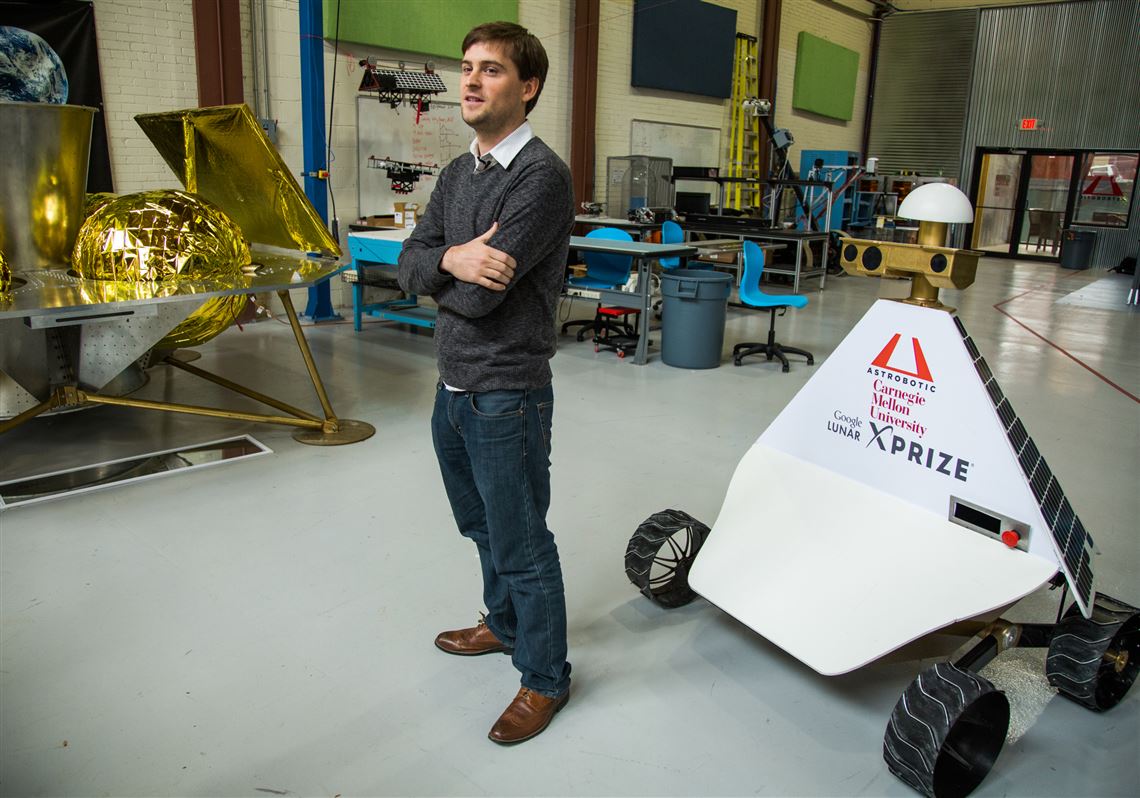 John Thornton, CEO of Astrobotic, stands in front of the company's Griffin Lander, left, and the Red Rover, right, at its headquarters in the Strip District.