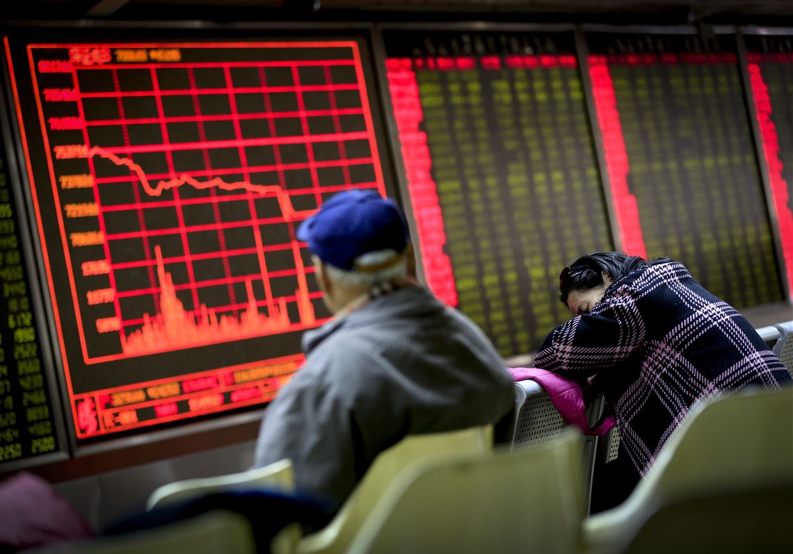 A woman takes a nap as a man looks at an electronic board displaying stock prices at a brokerage house in Beijing, Monday, Jan. 4, 2016. Shanghai's stock index plunged nearly 7 percent on Monday, sparking a halt in trading of Chinese shares, after weak manufacturing data and Middle East tensions weighed on Asian markets. (AP Photo/Andy Wong)