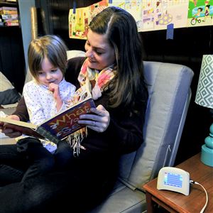 Jody Handley reads to her daughter Gillian Cowey, 4, while the CMU Speck pollution monitor sits on a table in her home in Squirrel Hill.