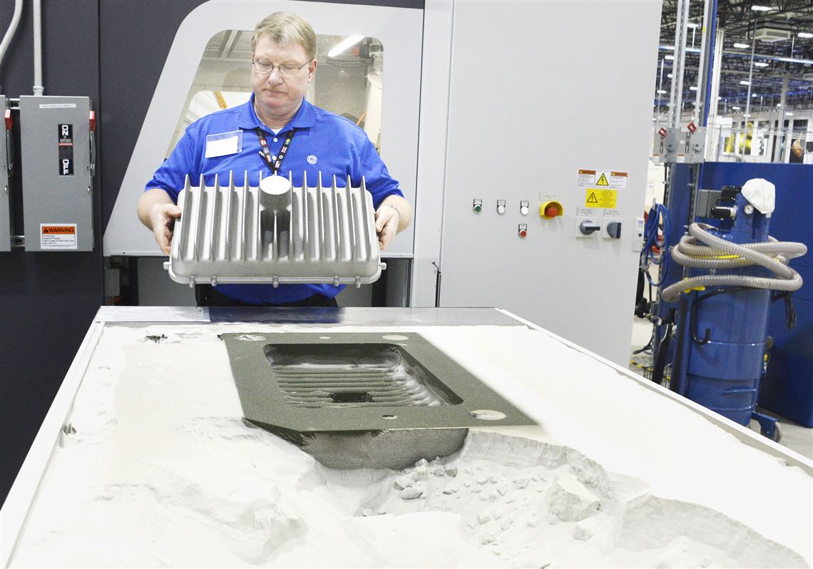 David Miller lifts one of the light housings in GE's “sand binder jetting”  area  at the new Center for Additive Technology Advancement.