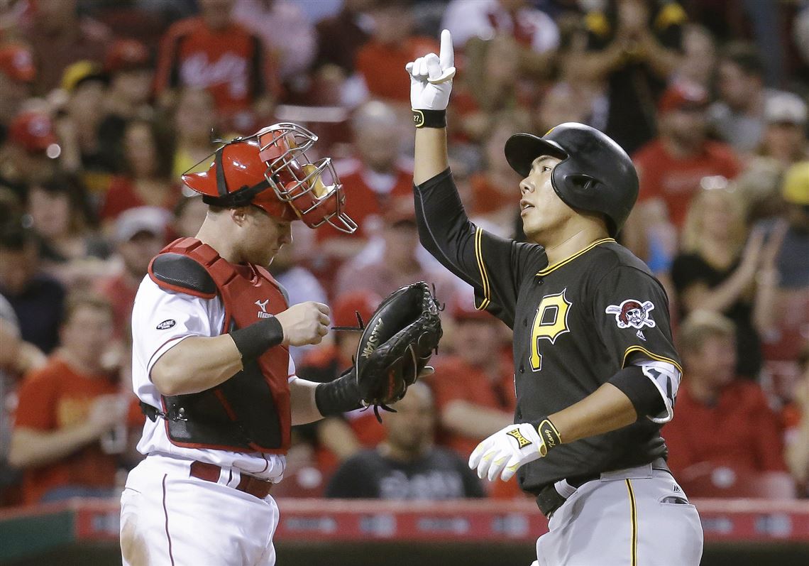 Jung Ho Kang passes Reds catcher Tucker Barnhart as he celebrates hitting a solo home Wednesday in Cincinnati.