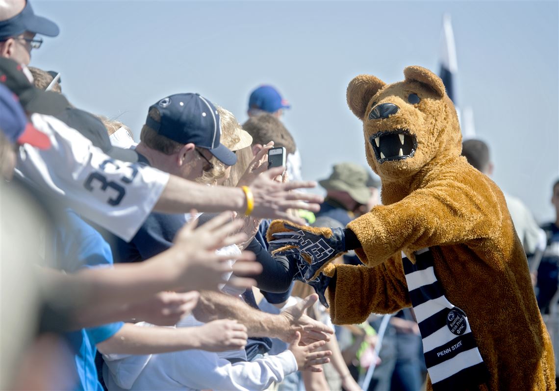 The Penn State Nittany Lion mascot high-fives fans as the team arrives at Beaver Stadium for the Blue-White spring NCAA college football game.