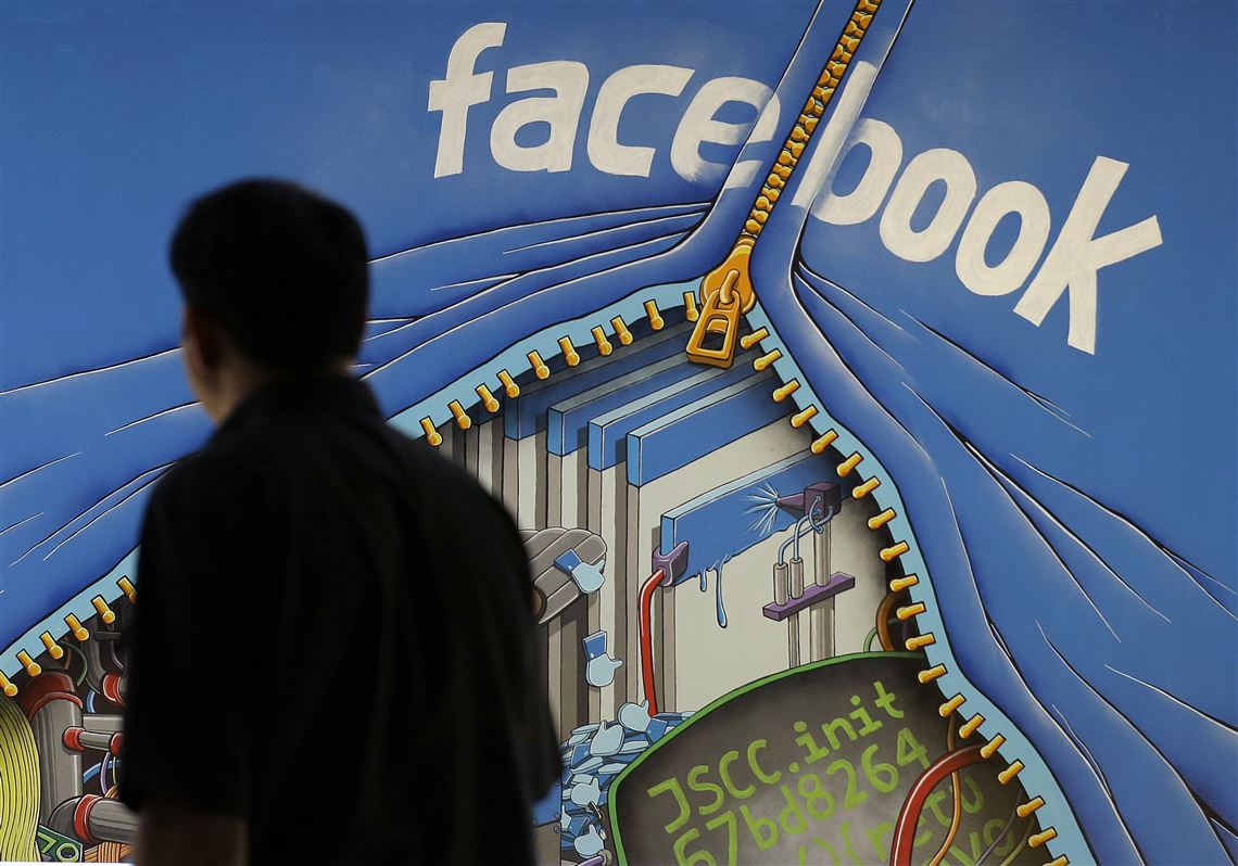 In this June 11, 2014, file photo, a man walks past a mural in an office on the Facebook campus in Menlo Park, Calif.