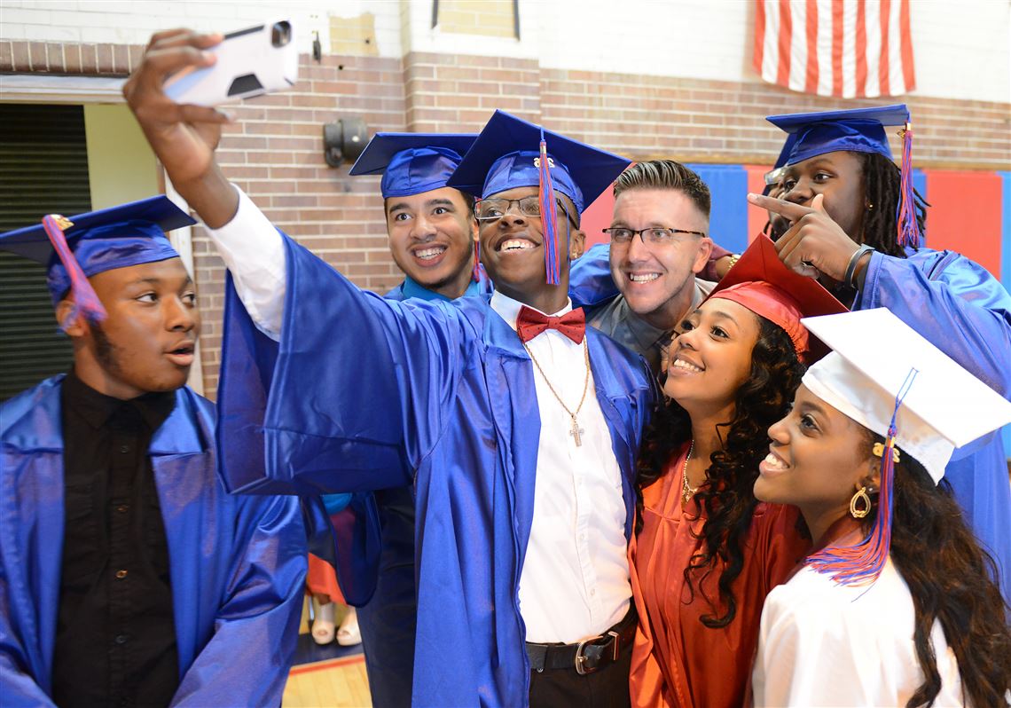 Seniors pose for a photograph with Jason Boll, an English teacher, before commencement at Wilkinsburg High School in June. 