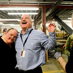 Steven Fekete, left, gives a hug to Tim Miller, center, at the Westmoreland County Blind Association in Greensburg.