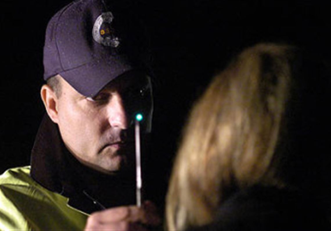 A Pittsburgh police officer conducts a field sobriety test at a roadside checkpoint.