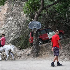 In this October 21, 2017, file photo, a resident rides a horse along a road that was hit by a mudslide during Hurricane Maria in Utuado, Puerto Rico.