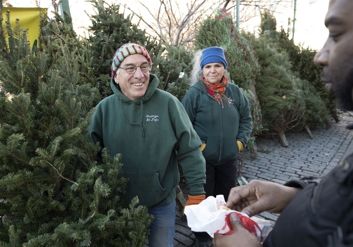 In this file photo, George Nash, left, and his wife, Jane Waterman, sell a tree to Kareem McGee outside Marcus Garvey Park in the Harlem neighborhood of New York on Dec. 7, 2017.