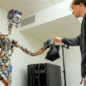 Disney Research associate Matthew Glisson hands a bag to a robot during a simulated demonstration at the Disney Research lab on the Carnegie Mellon University campus in Oakland. Researchers have developed a robot that is capable of analyzing human motions in order to give and receive items.