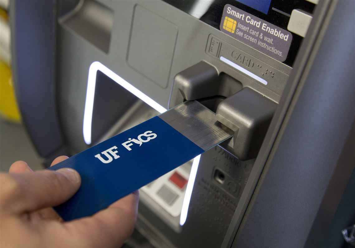 In this April 18, 2018, photo, a detective with the New York City Police Department uses a detection device that indicates if a credit card skimmer is in use at an ATM machine at a New York convenience store. The device is under development by the Florida Institute for Cybersecurity Research. (AP Photo/Mark Lennihan)