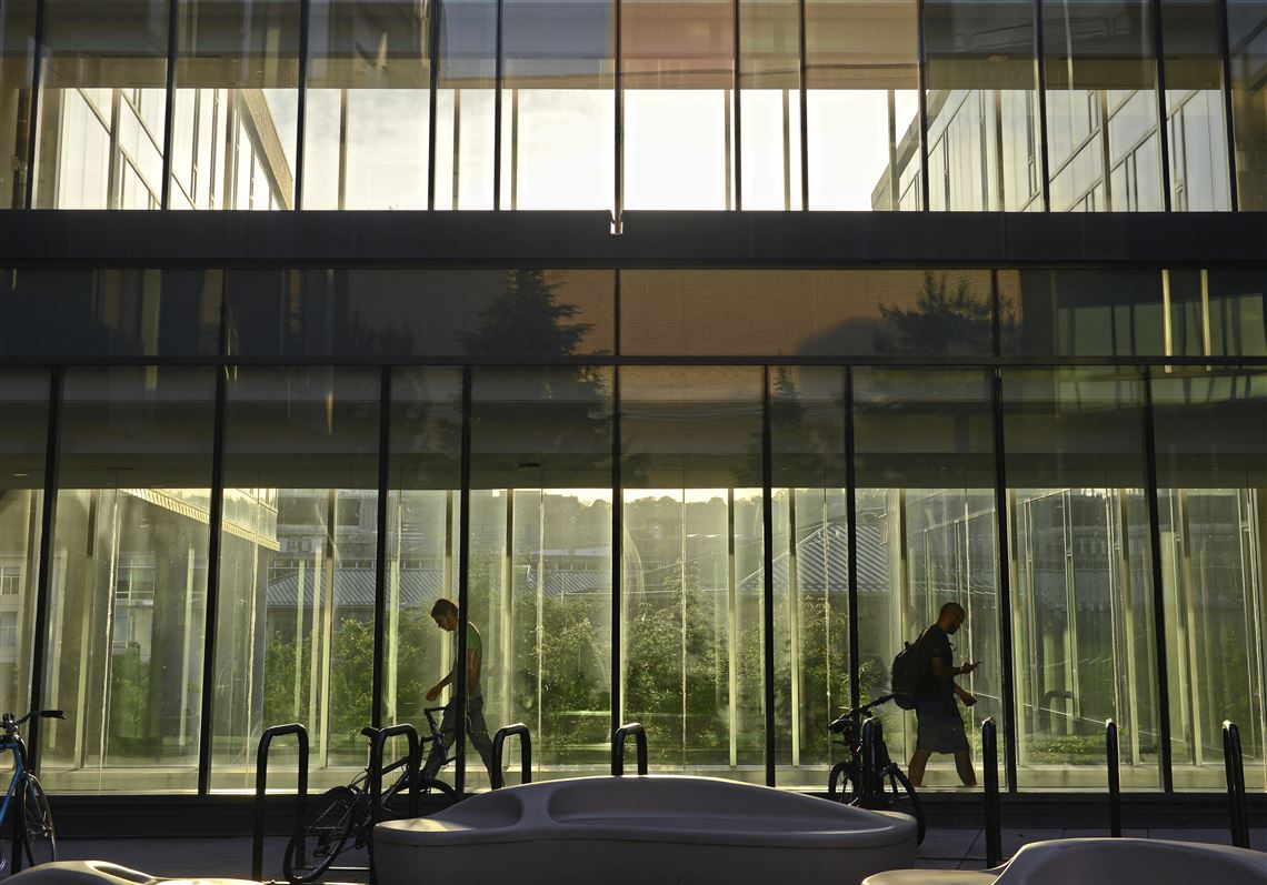 Two men are silhouetted by the setting sun as they walk through the Gates Center for Computer Science on Thursday.