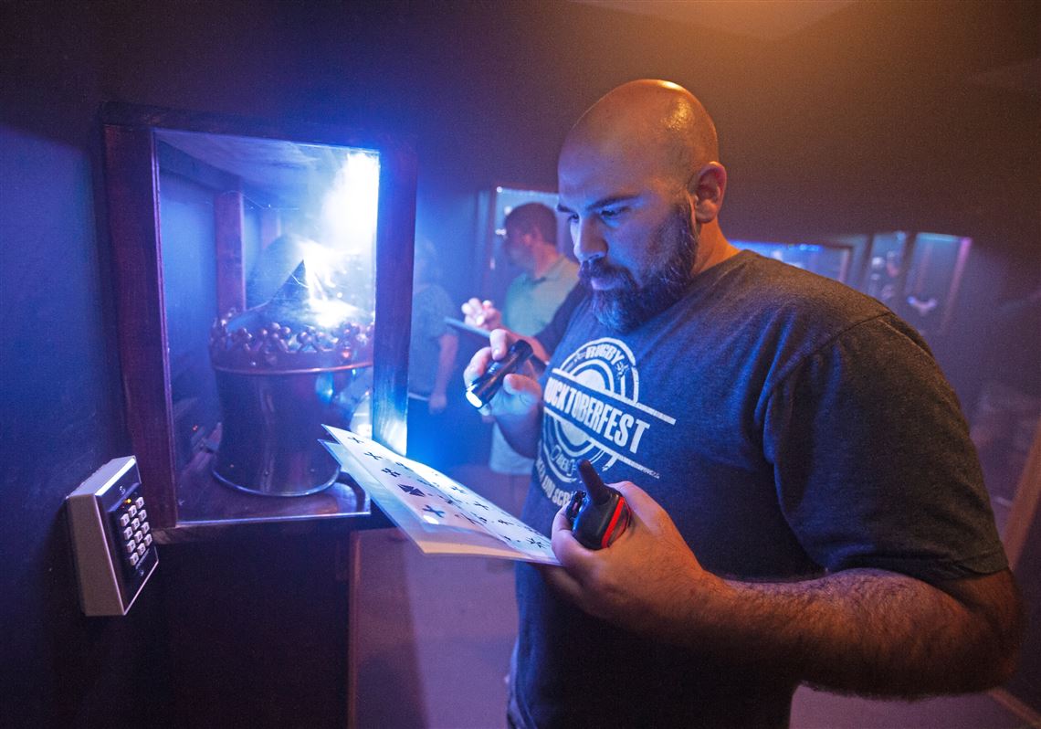 Daniel Lamego uses a flashlight in an attempt to decipher a code as part of an escape room he participated in with his co-workers last month in Jefferson Hills. Escape rooms are rising in popularity as an interactive form of entertainment, where participants try to accomplish a task by solving various clues while under a time limit.