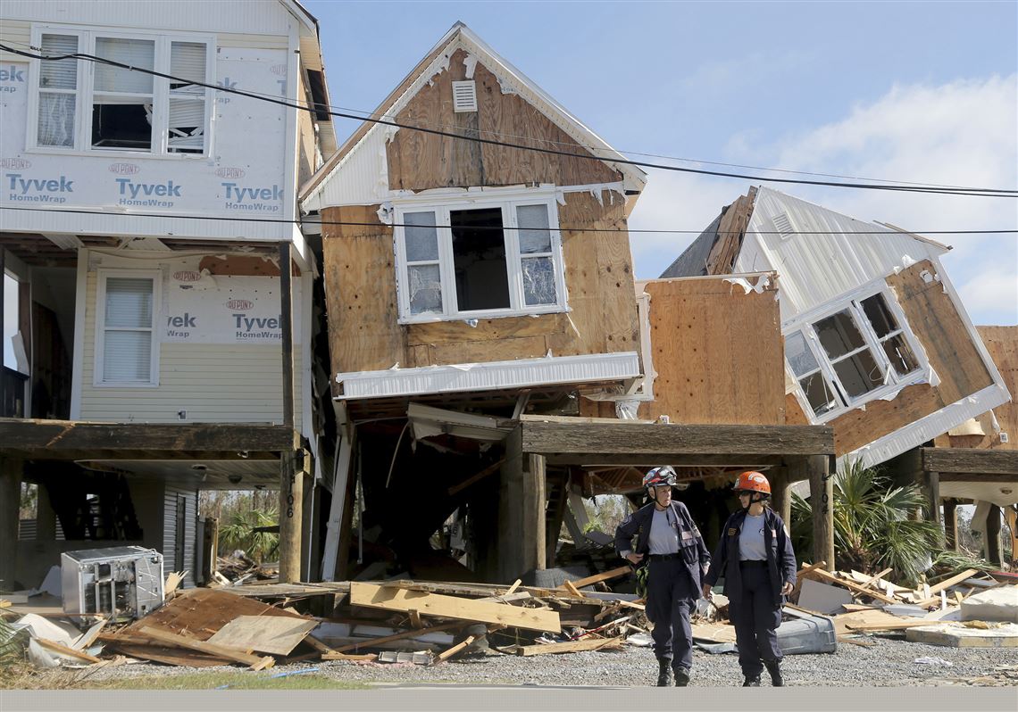 Emergency workers Dr. Patricia Cantrell, left, and Ana Kaufmann, with the South Florida Search and Rescue Task Force 2, survey damage at the western edge of town in Mexico Beach, Fla., after Hurricane Michael swept through the area Thursday, Oct. 11, 2018. (Douglas R. Clifford/Tampa Bay Times via AP)