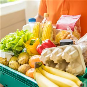 Grocery store delivery man wearing an orange polo-shirt delivering food to a customer at home