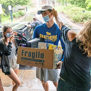 Nicole Wertz, right, helps her son, Brendan, adjust his mask as he helps his sister, Bailey, left, move into her dorm room at Chatham University on Aug. 18, 2021