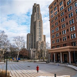 A student walks on the mostly empty University of Pittsburgh campus on the first day of spring semester classes on Monday, Jan. 10, 2022.