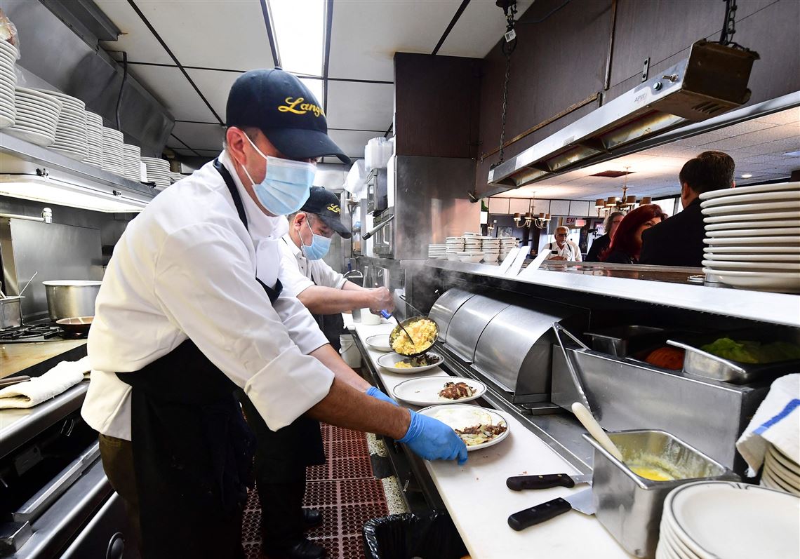 Signs are mounting that many Americans in highly vaccinated places are grasping for a near-normal life, even as the most contagious COVID-19 surge yet passes over. In this photo taken on June 15, 2021 kitchen staff continue wearing facemasks while preparing breakfast at Langer's Delicatessen-Restaurant in Los Angeles, California.