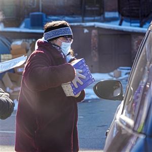Elaine Kulman, CFO of Metro Community Health Center, passes out boxes of COVID tests during a a drive-thru COVID-19 rapid at-home test distribution event on Wallace Avenue in Wilkinsburg on Friday, Jan. 21, 2022. 