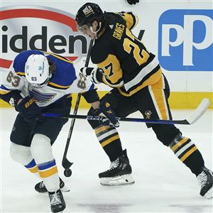 St. Louis Blues' Jake Neighbours (63) fights for thse puck against Pittsburgh Penguins' Ryan Graves (27) during the first period of an NHL hockey game Saturday, Dec. 30, 2023, in Pittsburgh. 