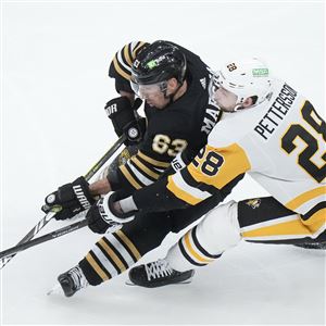 Boston Bruins left wing Brad Marchand (63) and Pittsburgh Penguins defenseman Marcus Pettersson (28) vie for control of the puck in the third period of an NHL hockey game, Thursday, Jan. 4, 2024, in Boston.