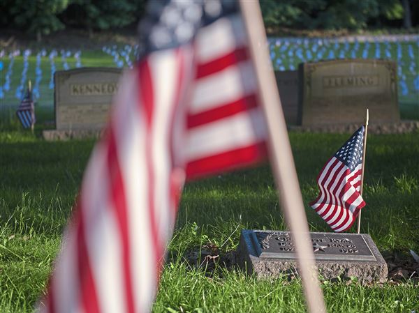 Evening light illuminates flags placed on the gravesites of veterans in advance of Memorial Day at the Allegheny Cemetery in Lawrenceville in 2018.