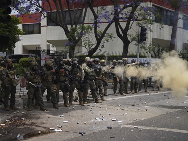 Border Patrol personnel deploy tear gas Saturday during a demonstration over the dozens detained in an operation by federal immigration authorities a day earlier in the Paramount section of Los Angeles.