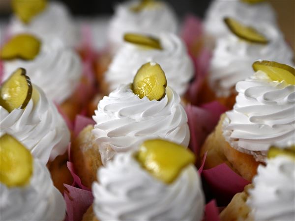 Patti Schvabenitz puts a single pickle slice on top of  special cupcakes Patti’s Pastries serves at Picklesburgh.