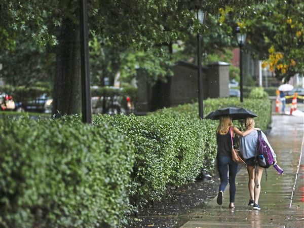 Friends and University of Pittsburgh students Shannon Lavender, 20, left, and Sophie Gysling, 19, right, share an umbrella as they walk through the rain Thursday, Oct. 4, 2018, at Schenley Plaza in Oakland. 