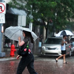 Pedestrians brace from the rain as they cross 9th Street Downtown on Monday, July 7. 2025.