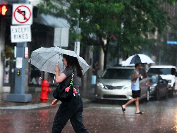 Pedestrians brace from the rain as they cross 9th Street Downtown on Monday, July 7. 2025.