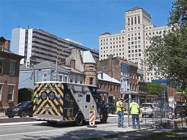 An ambulance passes a construction crew working on the lane reduction project on North Avenue by Allegheny General Hospital on the North Side Tuesday, July 22, 2025.