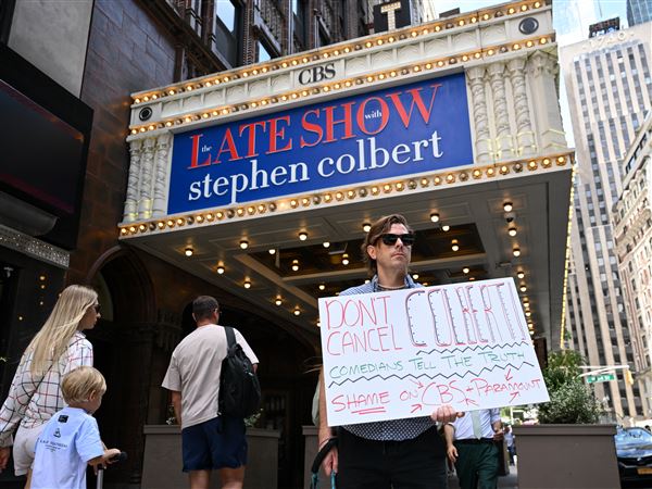 A demonstrator holds a sign in support of Stephen Colbert outside the Ed Sullivan Theater, where "The Late Show with Stephen Colbert" is produced, in New York City on July 18, 2025. 