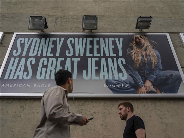 People walk past a campaign poster starring Sydney Sweeney which is displayed at the American Eagle Outfitters store, Friday, Aug. 1, 2025, in New York. 