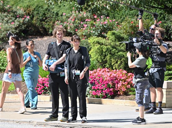 Actors Fiona Dourif and Lucas Iverson film exterior scenes from the HBO drama “The Pitt” as extras go by outside of Allegheny General Hospital on the North Side on Thursday.                                                      