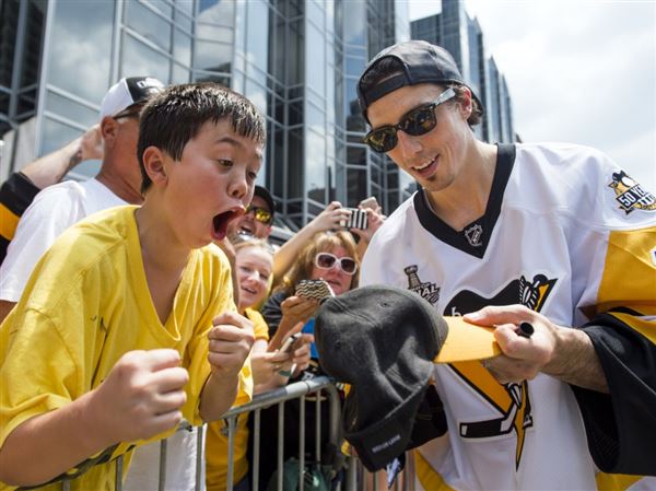Penguins' Marc-Andre Fleury signs a hat for a young fan during the Pittsburgh Penguins victory parade on Wednesday, June 14, 2017 at Grant Street and Boulevard of the Allies.